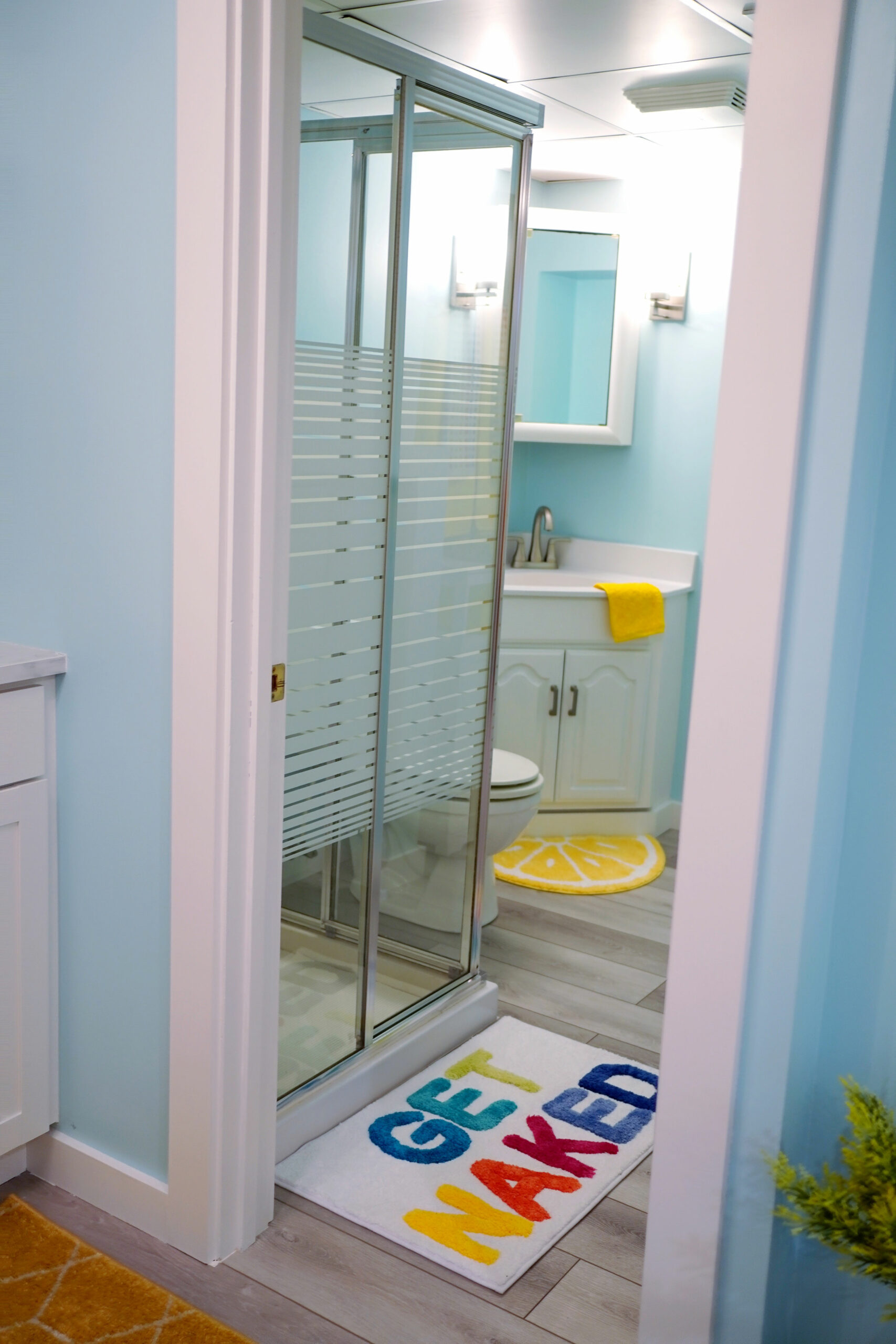 The bathroom was dark and dingy. (That linoleum, though!) So, new vinyl plank flooring immediately brightened it up, with new bathroom hardware and touches of lemon yellow to add joy on a tight budget.